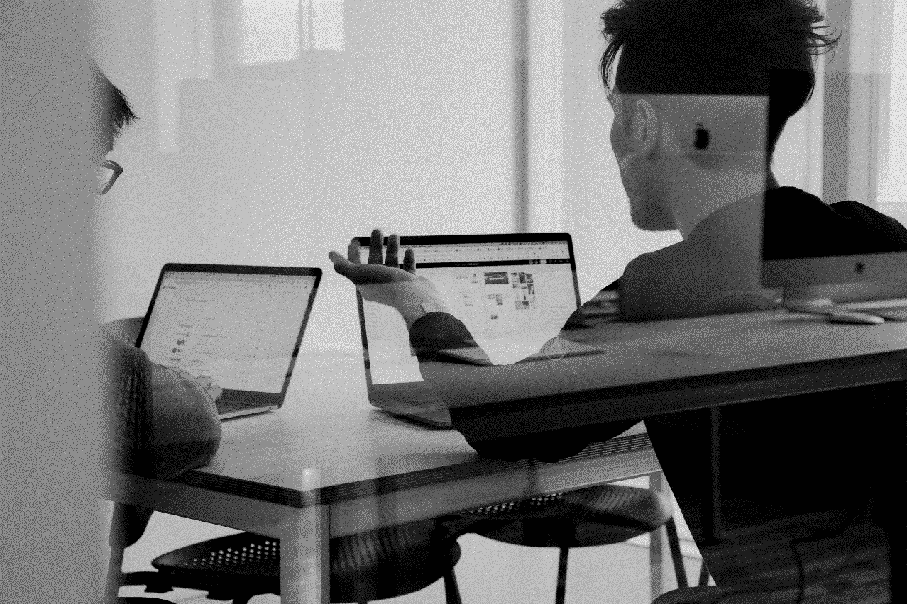 Deux personnes assises à une table, travaillant sur des ordinateurs portables. L'Arcep et l'Arcom publient le RGESN 2024.