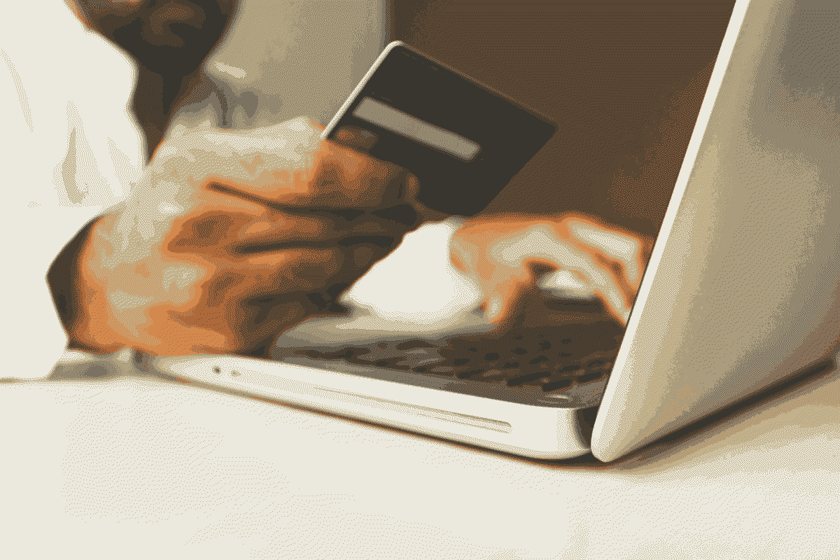 Un homme tient une carte de crédit et un ordinateur portable, utilisant Click to Pay sur Prestashop.