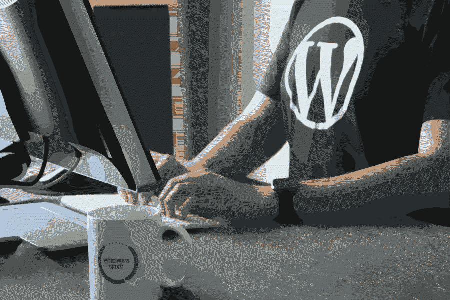 Un homme assis à un bureau, utilisant un ordinateur, avec une tasse de café à côté de lui.